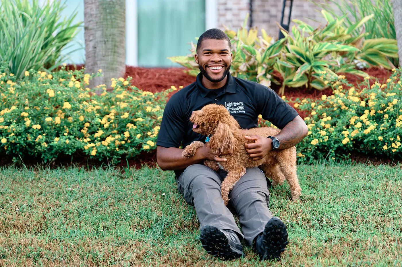 Walter Bell smiling on the grass with a red poodle puppy in his lap